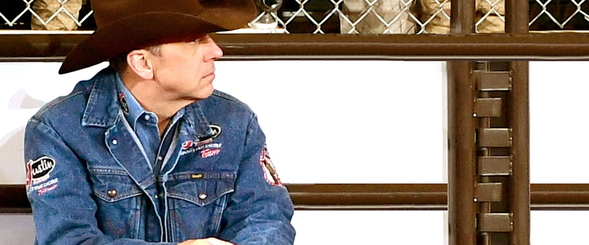 Man in cowboy hat and jean jacket looks into the distance 